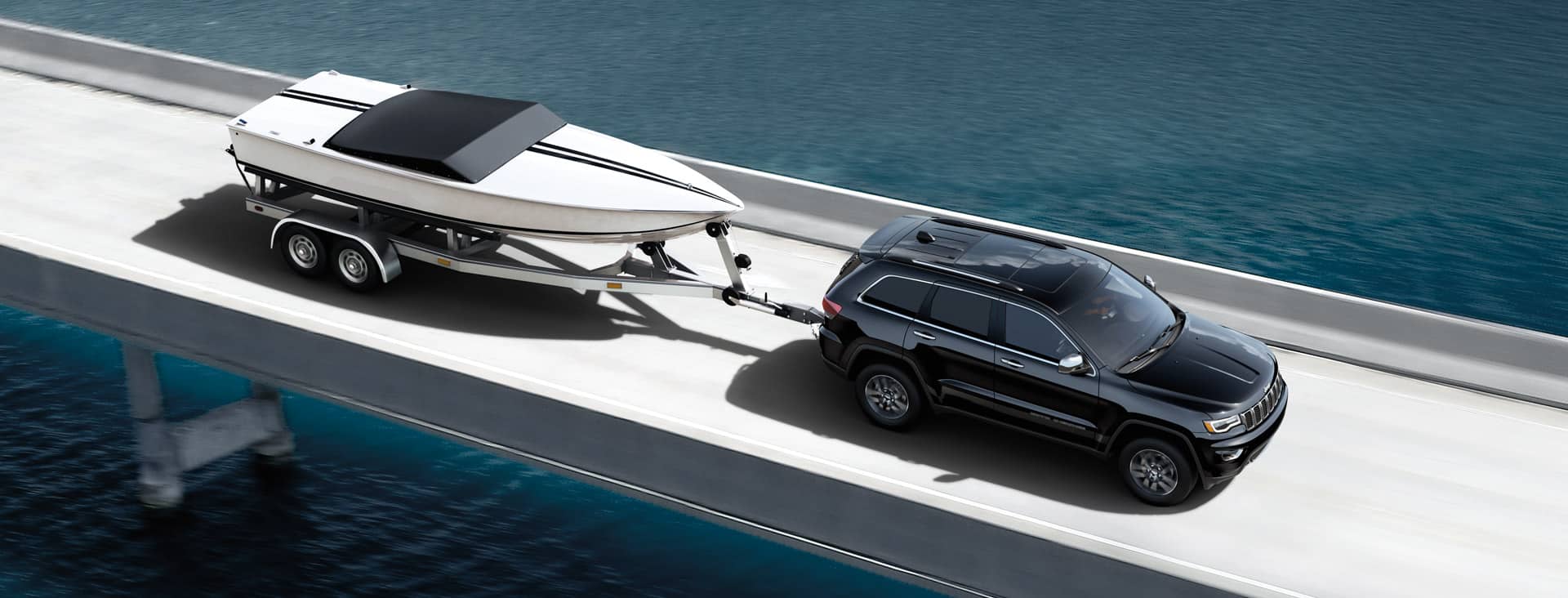 Overhead view of Jeep Grand Cherokee towing a boat across a bridge.