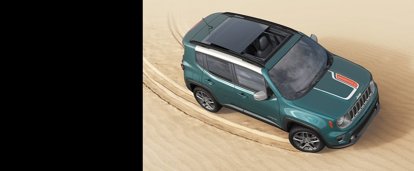 An overhead view of a teal 2021 Jeep Renegade Islander with its sunroof open, being driven on sand.