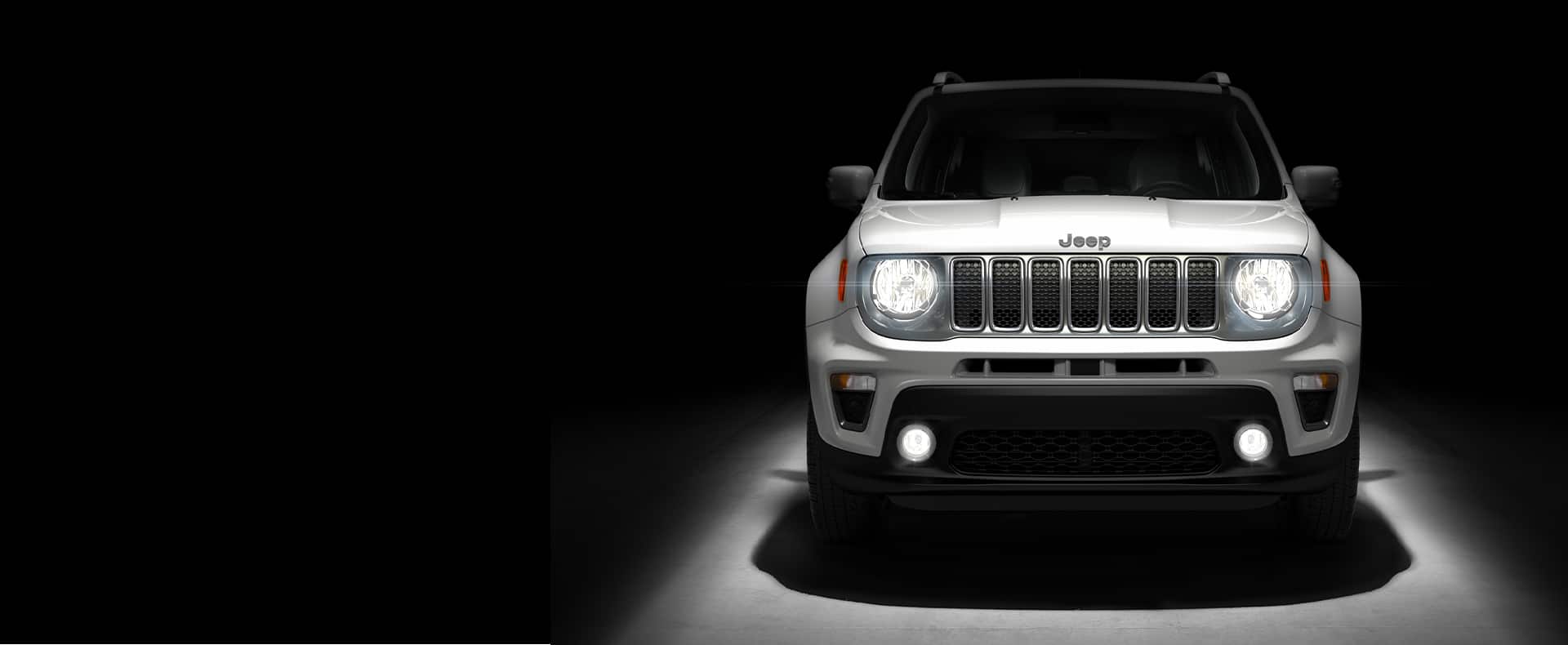Head-on view of 2021 Jeep Renegade with its headlamps and fog lamps illuminated.