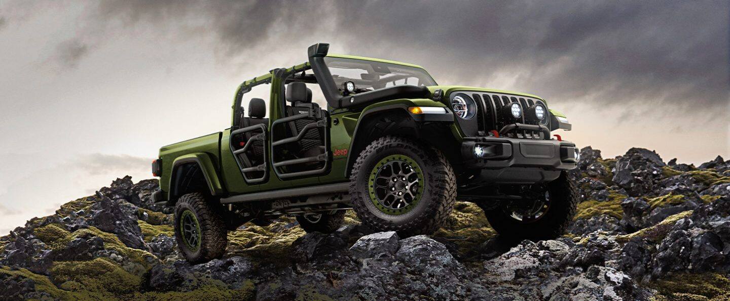 The 2021 Jeep Gladiator with available tube doors, hood snorkel and open roof, parked on rocks.