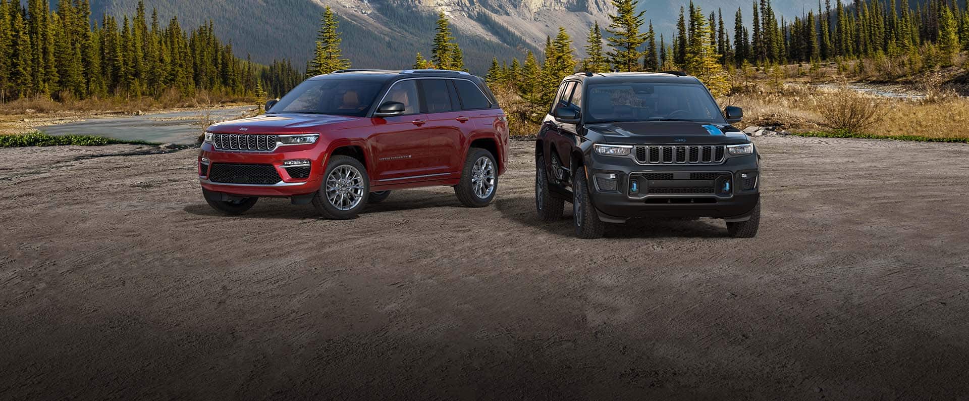 Un Jeep Grand Cherokee Summit y un Grand Cherokee Trailhawk 4xe 2022 estacionados en un valle arenoso con montañas de fondo.