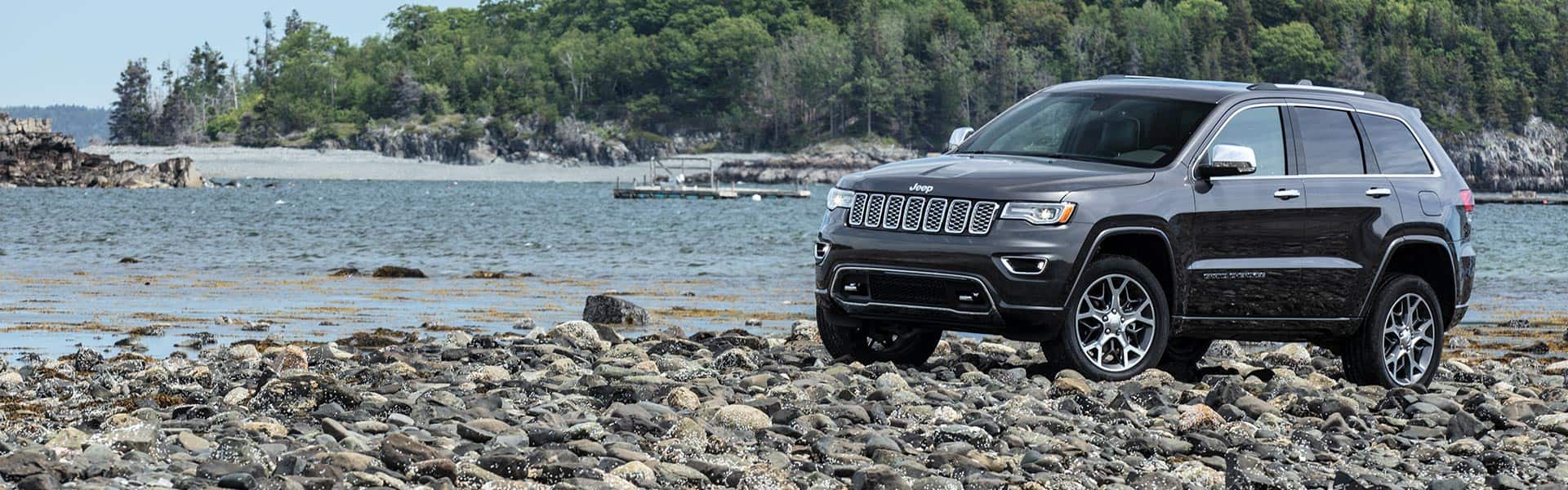 The 2021 Jeep Grand Cherokee Limited parked on a rocky beach.