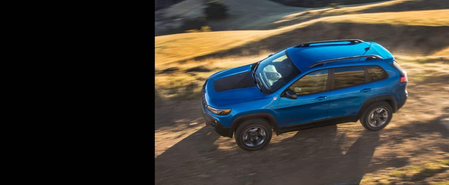 The 2021 Jeep Cherokee Trailhawk being driven off-road on a dirt road.