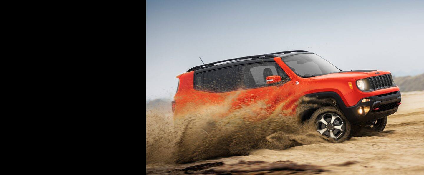 El Jeep Renegade Trailhawk 2021 andando en modo todoterreno en un terreno arenoso con una nube de polvo que sale de sus ruedas.