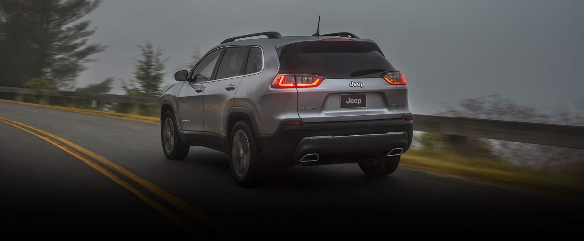 The 2022 Jeep Cherokee Limited being driven on a wet road under an overcast sky.