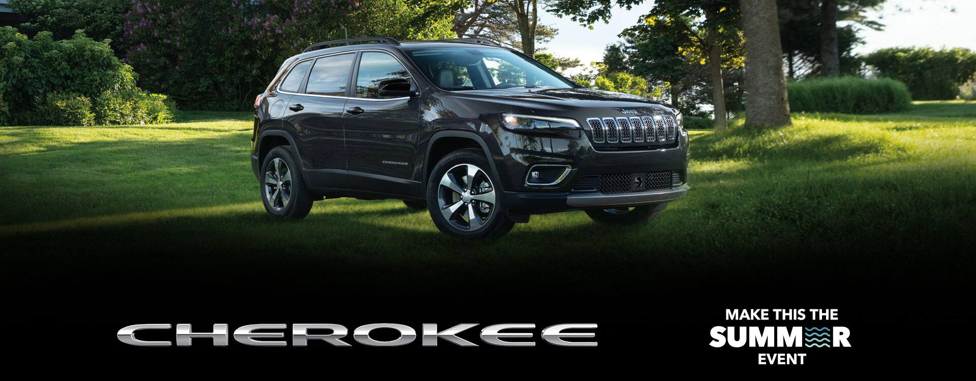 The 2022 Jeep Cherokee Limited in a park, parked on the grass. The Make This The Summer Event logo.