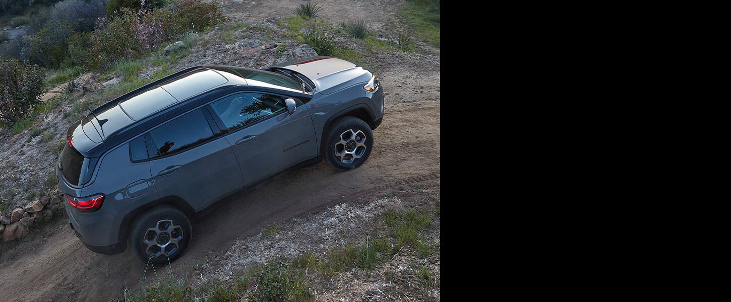 The 2022 Jeep Compass Trailhawk ascending a hill on a dirt trail.