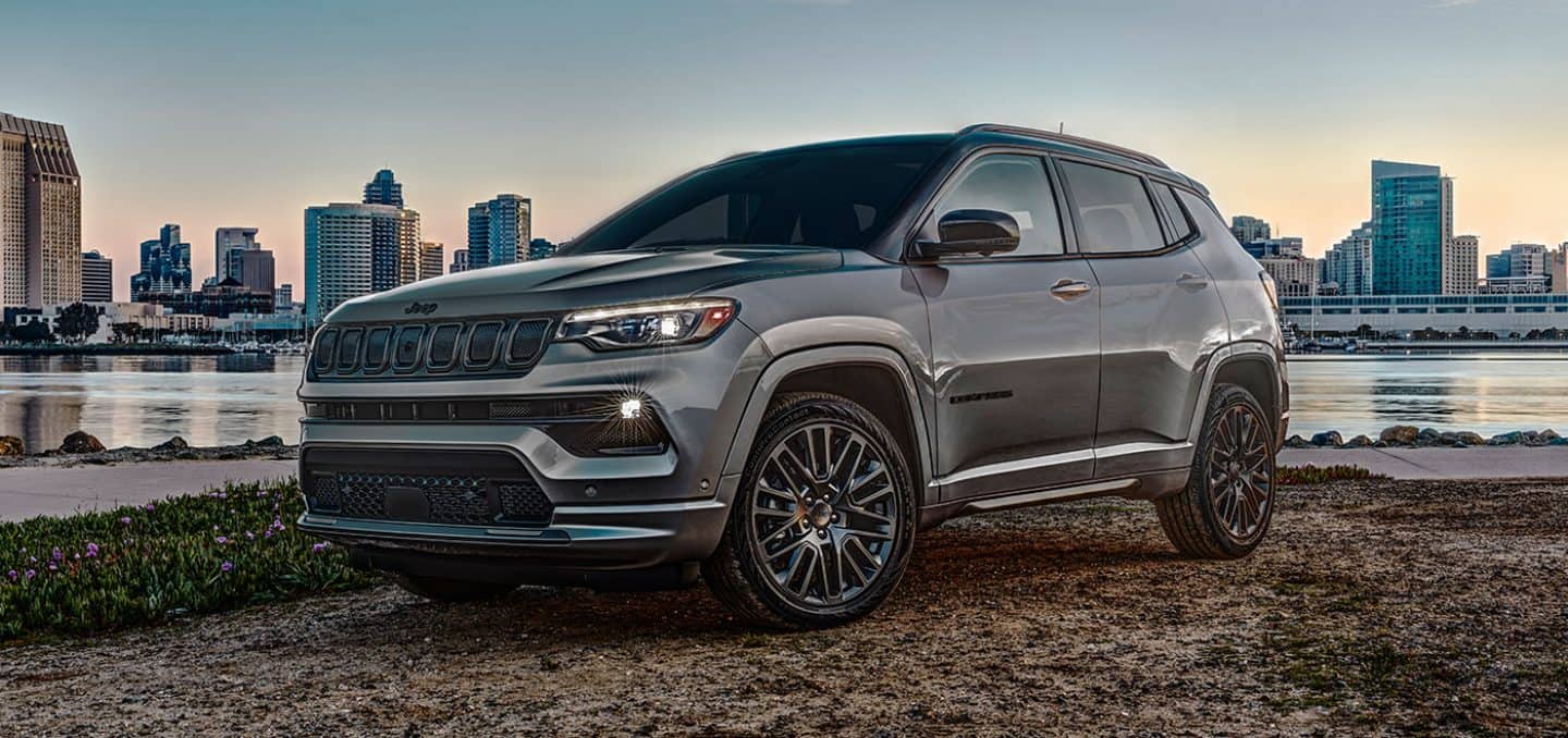 The 2022 Jeep Compass High Altitude parked by a river with a city skyline behind it.