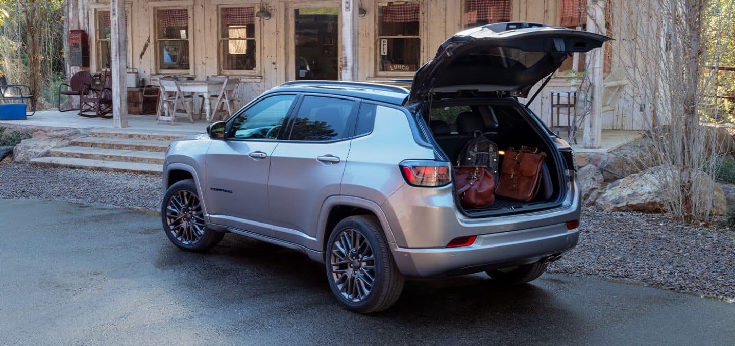 Display The 2022 Jeep Compass High Altitude with its liftgate open to reveal its cargo compartment filled with luggage.