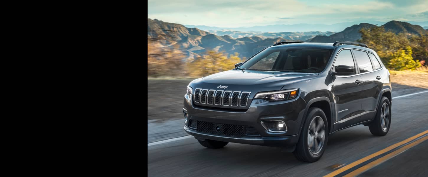 The 2022 Jeep Cherokee being driven on a highway with mountains in the background.