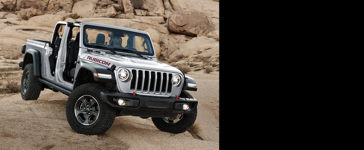 The 2022 Jeep Gladiator Rubicon with its doors off, being driven on uneven, rocky terrain.