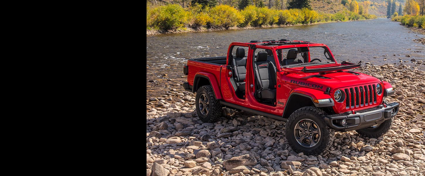 The 2022 Jeep Gladiator Rubicon with its top and doors off, parked on a rocky beach.
