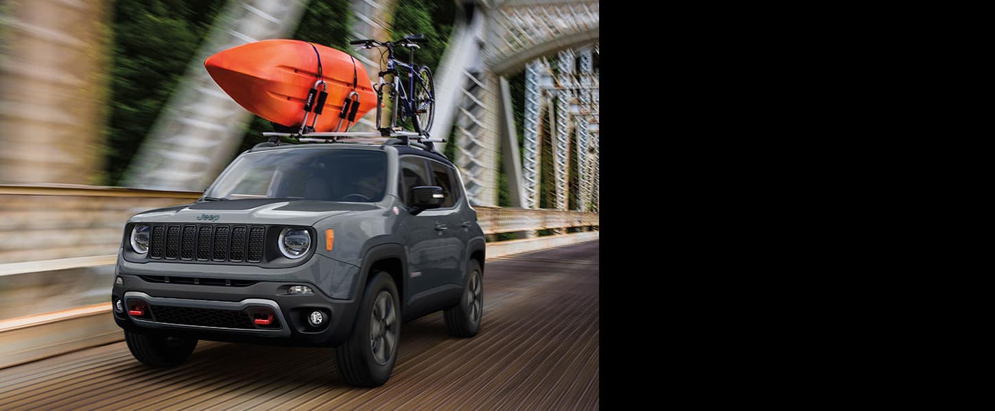The 2022 Jeep Renegade Trailhawk being driven with a kayak and a mountain bike mounted to its roof rack.