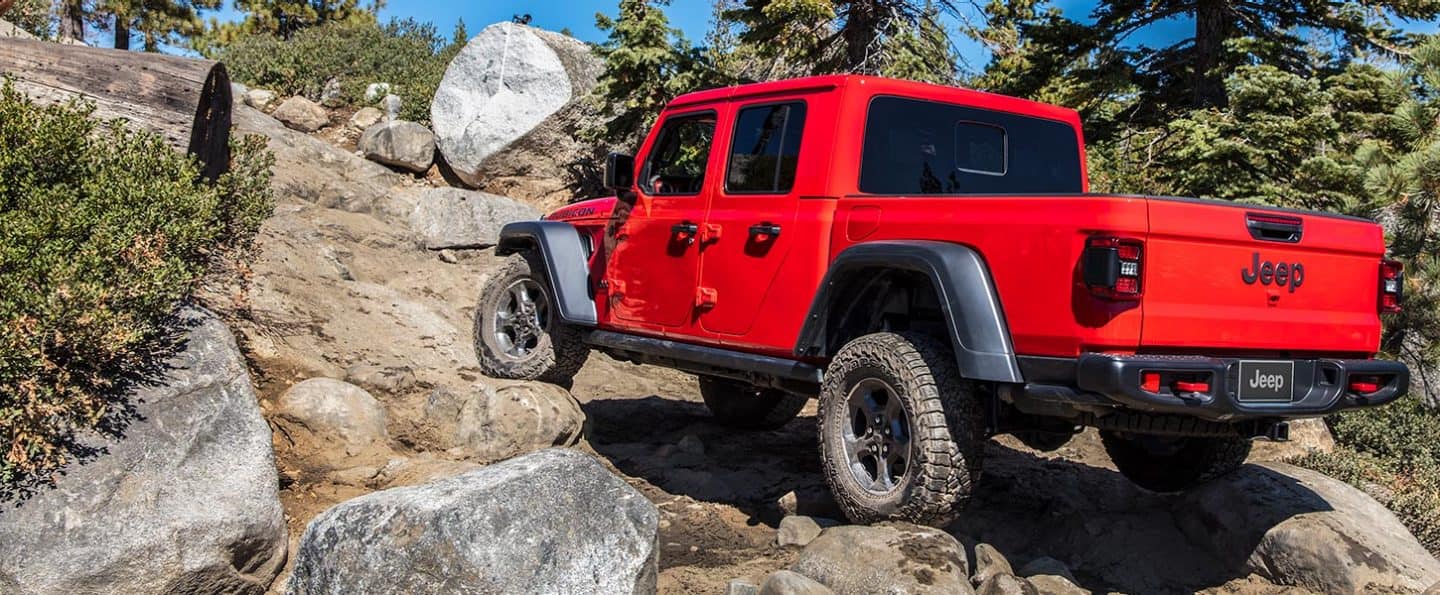 The 2022 Jeep Gladiator crawling over rocks with the front left wheel elevated.