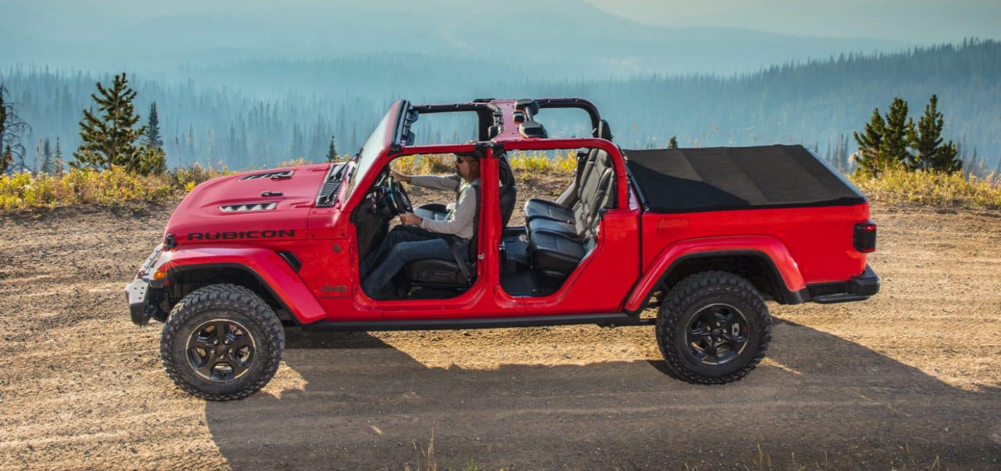 Display The 2022 Jeep Gladiator Rubicon being driven off-road on a mountain trail with its top and doors off.