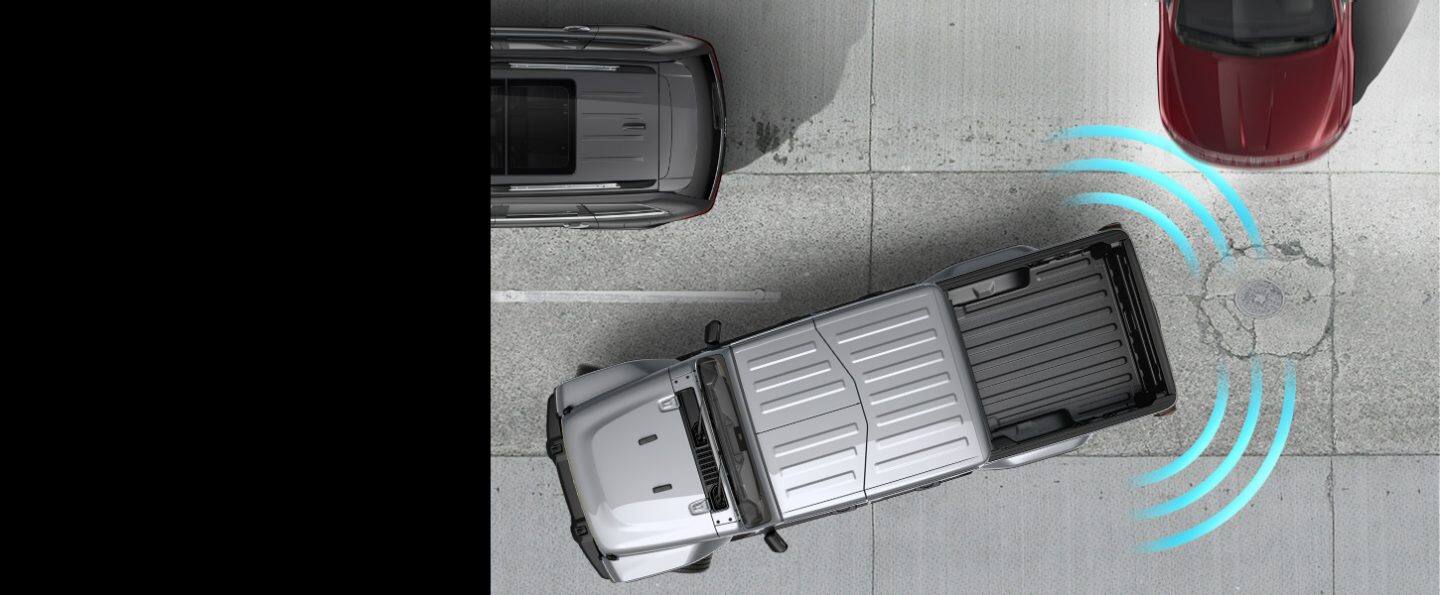 Illustrated sensor bars coming from the rear left and right of the 2022 Jeep Gladiator Overland, detecting a vehicle passing behind it as it reverses out of a parking space.