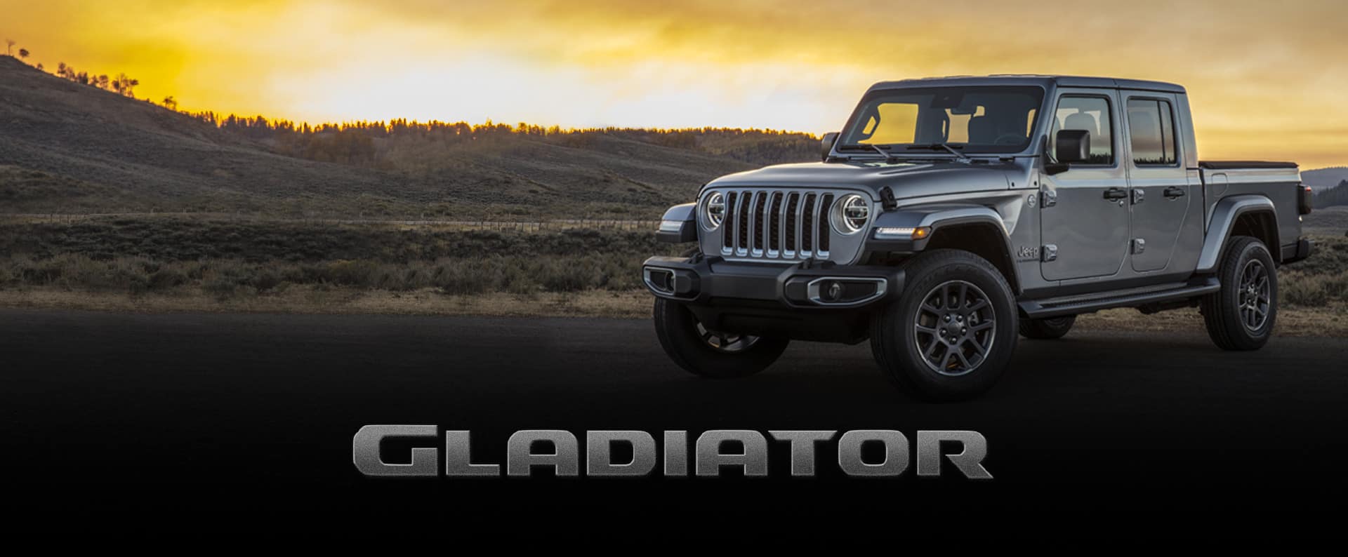 El Jeep Gladiator Overland estacionado al pie de una colina, mientras el sol se oculta a la distancia.