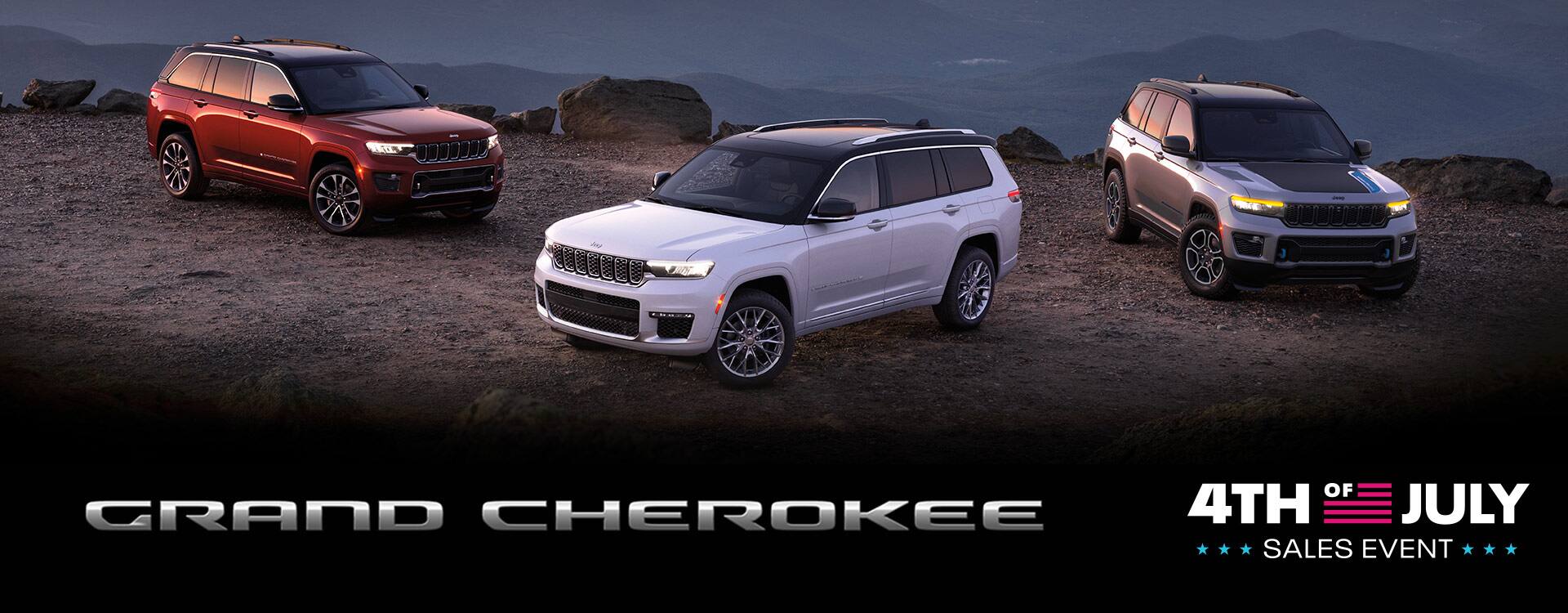 Three 2022 Jeep Grand Cherokee models with their headlamps on, parked on a cliff in the mountains at dawn. From left to right: Grand Cherokee Overland, Grand Cherokee L Summit and Grand Cherokee Trailhawk 4xe. The 4th of July Sales Event logo.