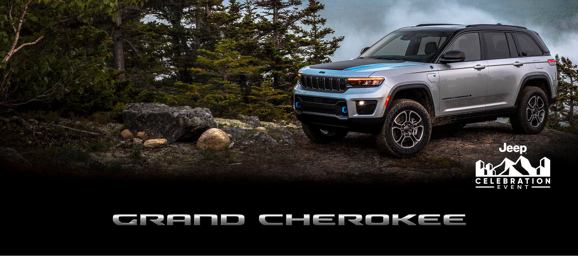 Un Jeep Grand Cherokee Trailhawk 4xe 2022 gris estacionado en una cumbre rocosa en las montañas con un cielo tormentoso encima. El evento de celebración de Jeep.