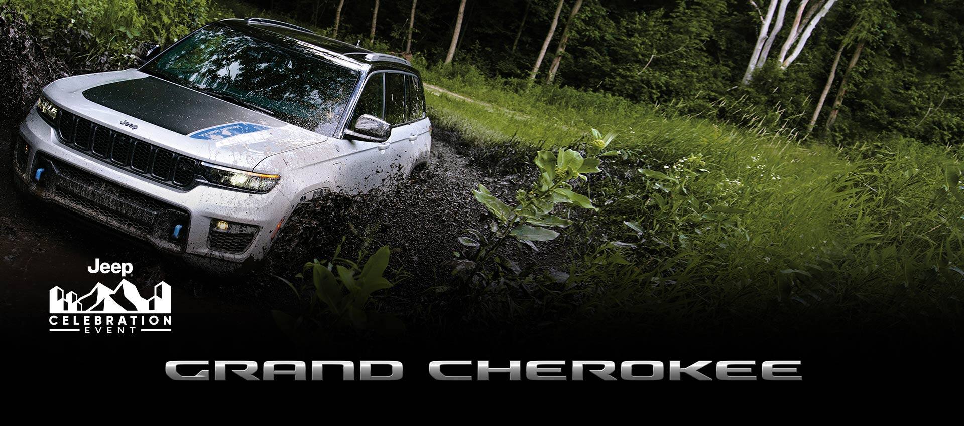 A white 2023 Jeep Grand Cherokee Trailhawk 4xe being driven through a muddy trail off-road, mud splashing up to the top of the wheel wells. Grand Cherokee. The Jeep Celebration Event.