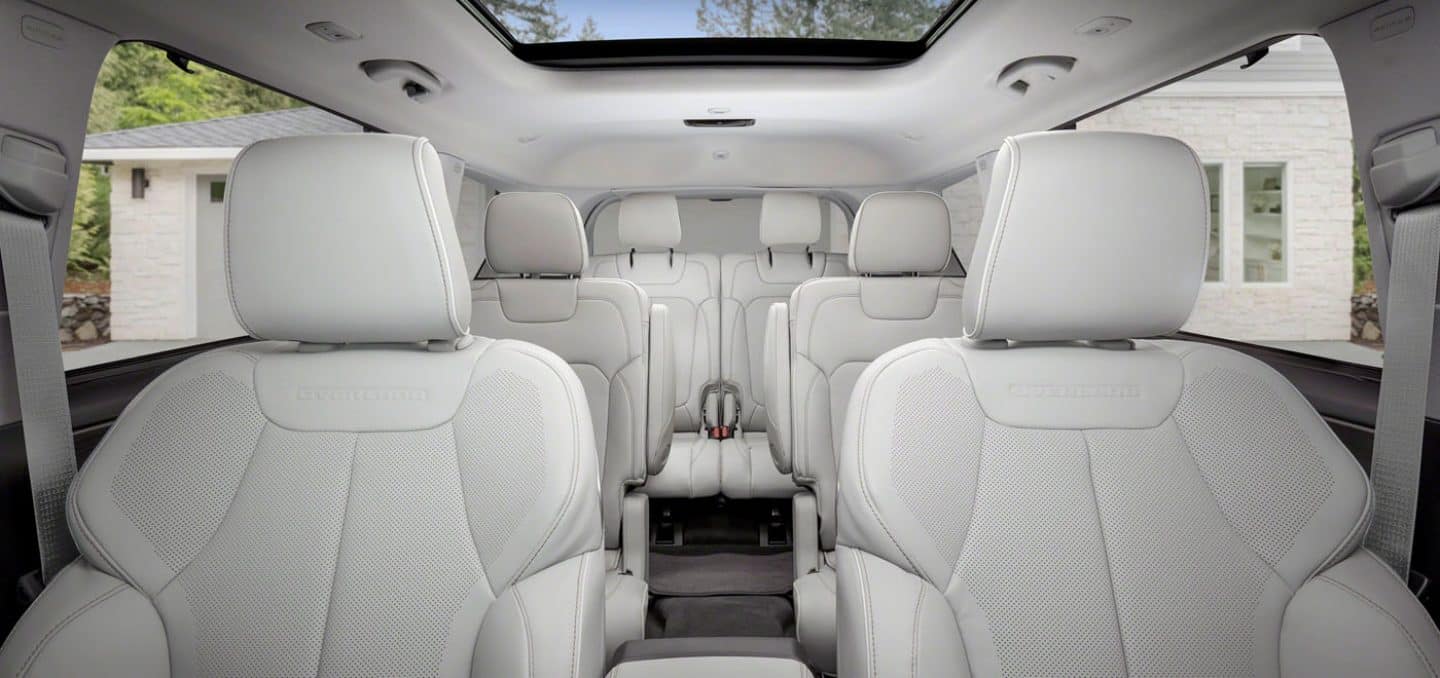Display The interior of the 2022 Jeep Grand Cherokee Overland with three rows of seating and an open sunroof.