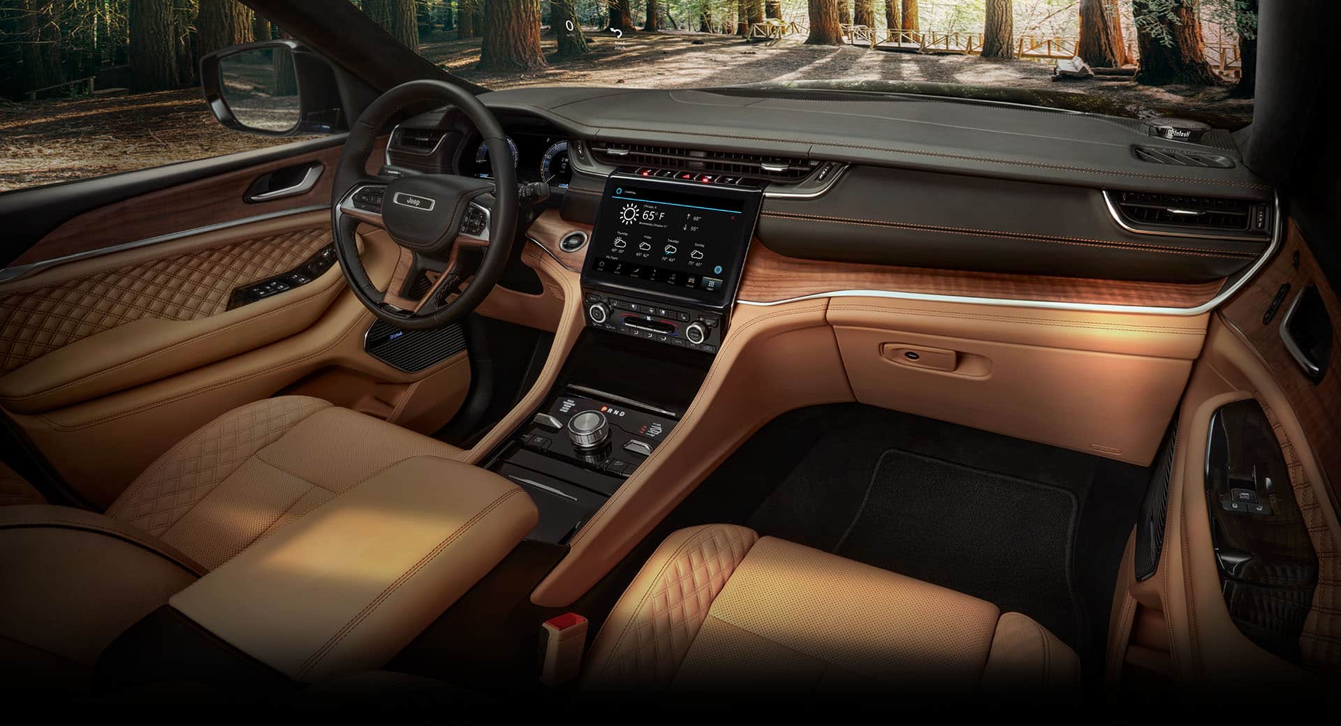 The front row of the 2022 Jeep Grand Cherokee Summit Reserve, in Tupelo Palermo leather, focusing on the steering wheel, touchscreen and dashboard.