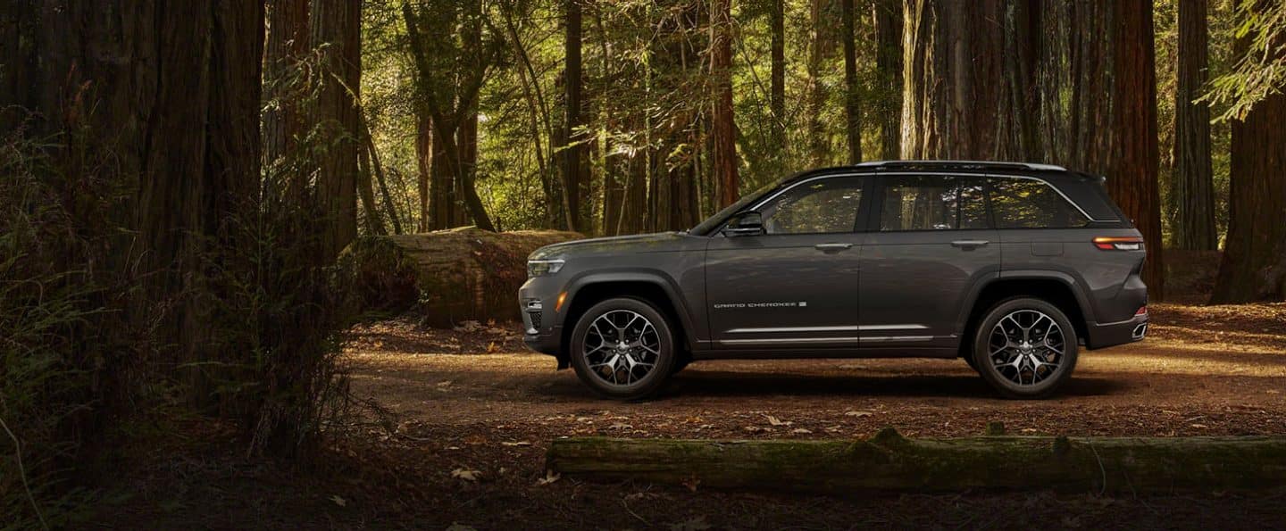 A side profile of the two-row 2022 Jeep Grand Cherokee Summit Reserve against a backdrop of trees, allowing the viewer to estimate its length.