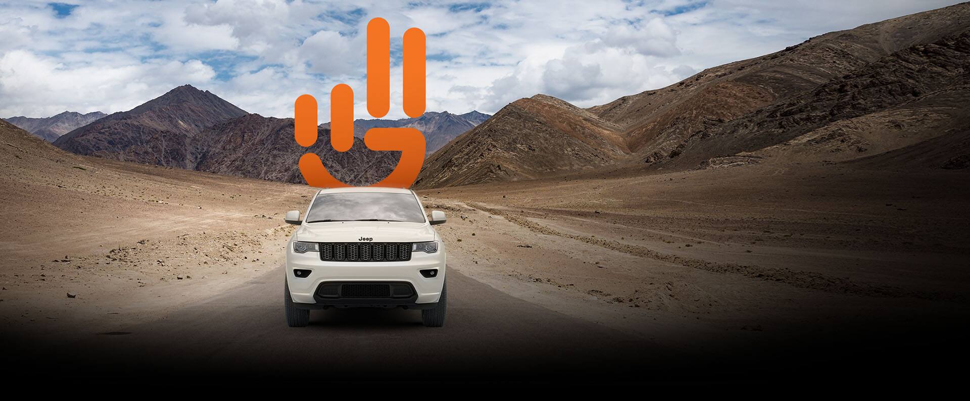Jeep Wave logo. A 2022 Jeep Grand Cherokee WK Laredo X with the Altitude Appearance Package being driven on a lonely desert road away from the mountains.