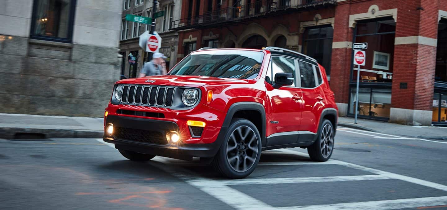 Display The 2022 Jeep Renegade Limited turning a corner at an intersection of two streets in an urban center.
