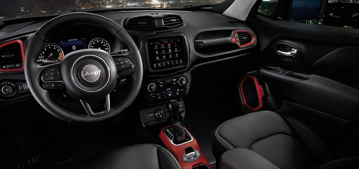 Display The interior of the 2022 Jeep Renegade Trailhawk focusing on the steering wheel, touchscreen and dashboard.