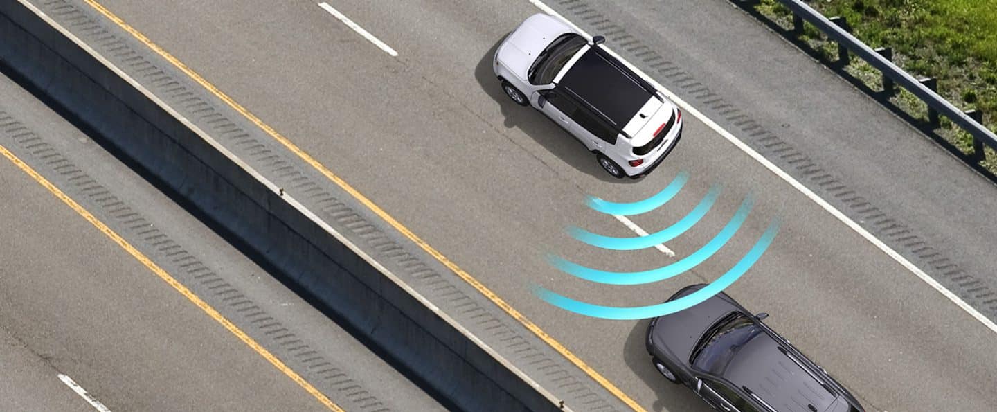 A bird's eye view of the 2022 Jeep Renegade with illustrated sensor bars coming from its rear left and detecting a vehicle in the next lane.
