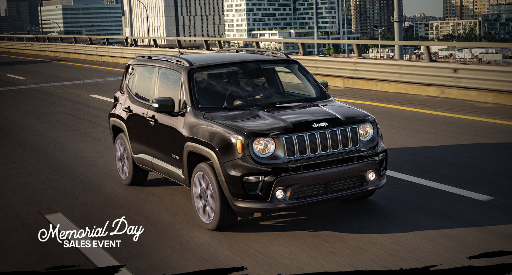 The 2022 Jeep Renegade Limited being driven on an overpass with a city view behind it. The Memorial Day Sales Event logo.