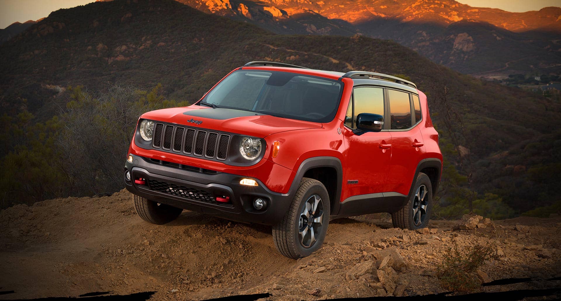 The 2022 Jeep Renegade Trailhawk parked on a dirt track in the mountains at dawn.