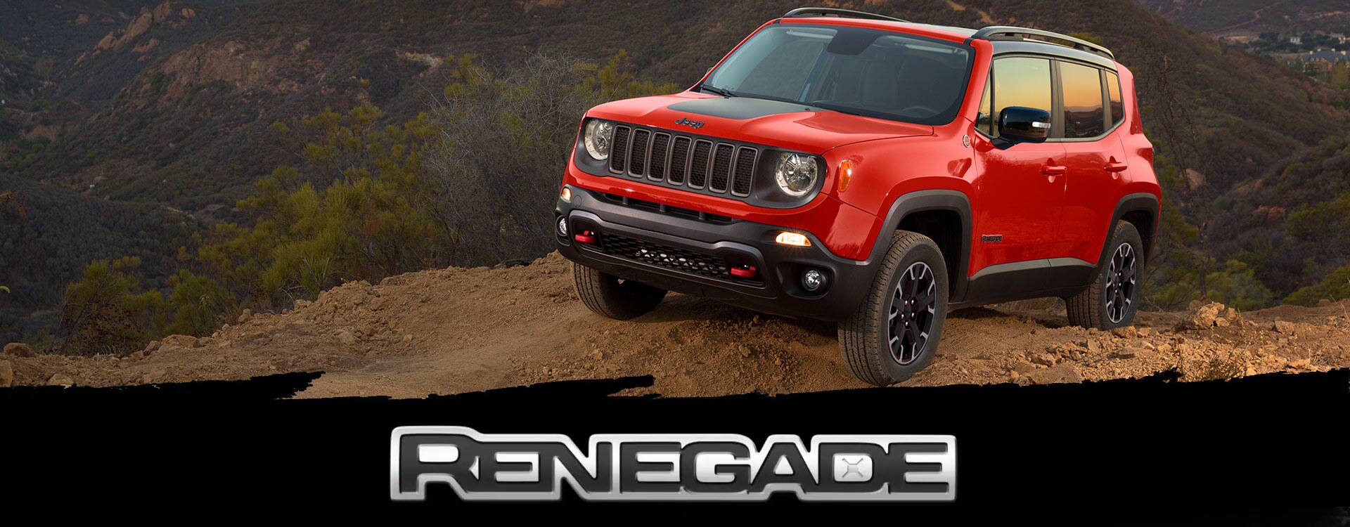 A red 2022 Jeep Renegade Trailhawk parked at the top of a hill off-road, with mountains in the background reflecting a shimmering sunset. 