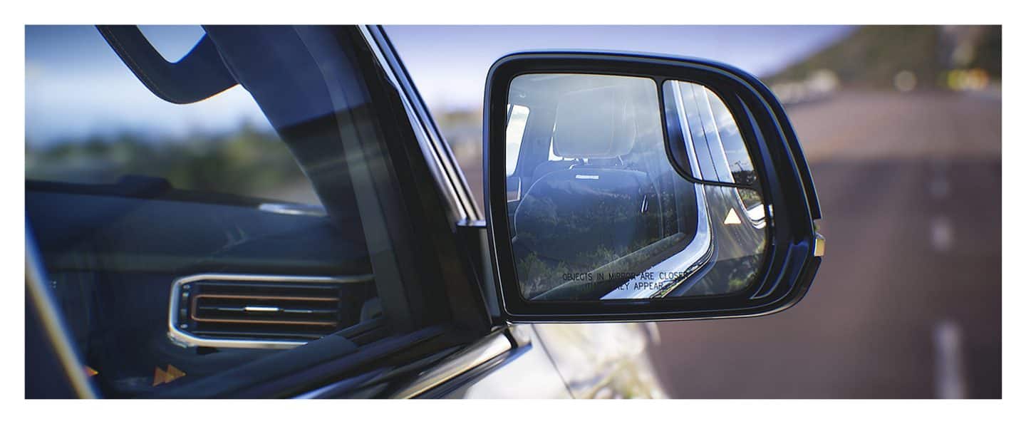 A close-up of the passenger-side exterior mirror on the 2022 Wagoneer with a blind spot alert displayed.
