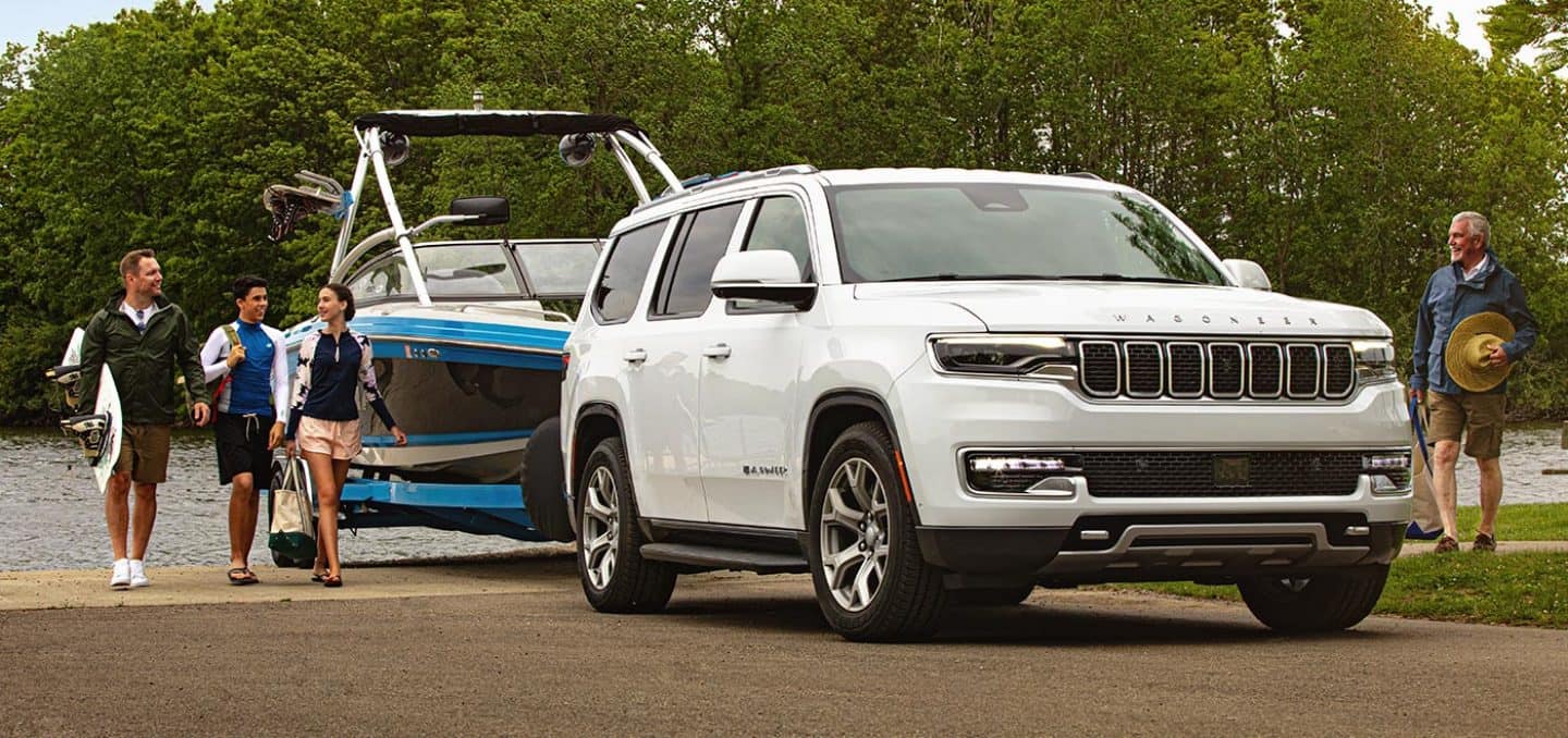 Display A 2022 Wagoneer towing a motorboat out of a lake.