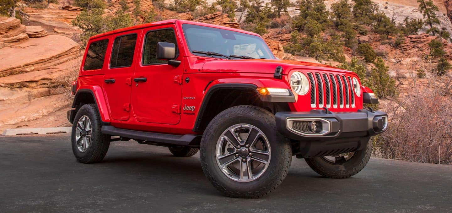 The 2022 Jeep Wrangler Sahara parked on a road in front of a scrubby desert backdrop.