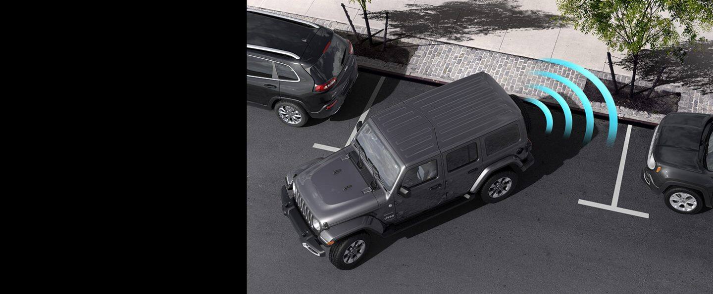 El Jeep Wrangler Sahara 2022 mientras retrocede hacia un lugar de estacionamiento en la acera, con barras de sensores ilustradas que emanan de su parte trasera.