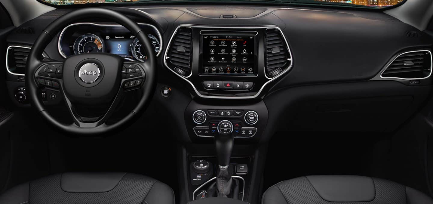 Display The interior of the 2023 Jeep Cherokee Altitude Lux focusing on the steering wheel, Digital Cluster Display, Uconnect touchscreen and center stack controls.
