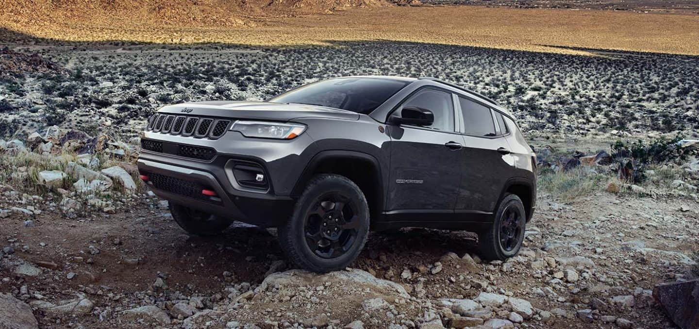 Display A 2023 Jeep Compass Trailhawk crawling over large and small rocks and stones off-road.