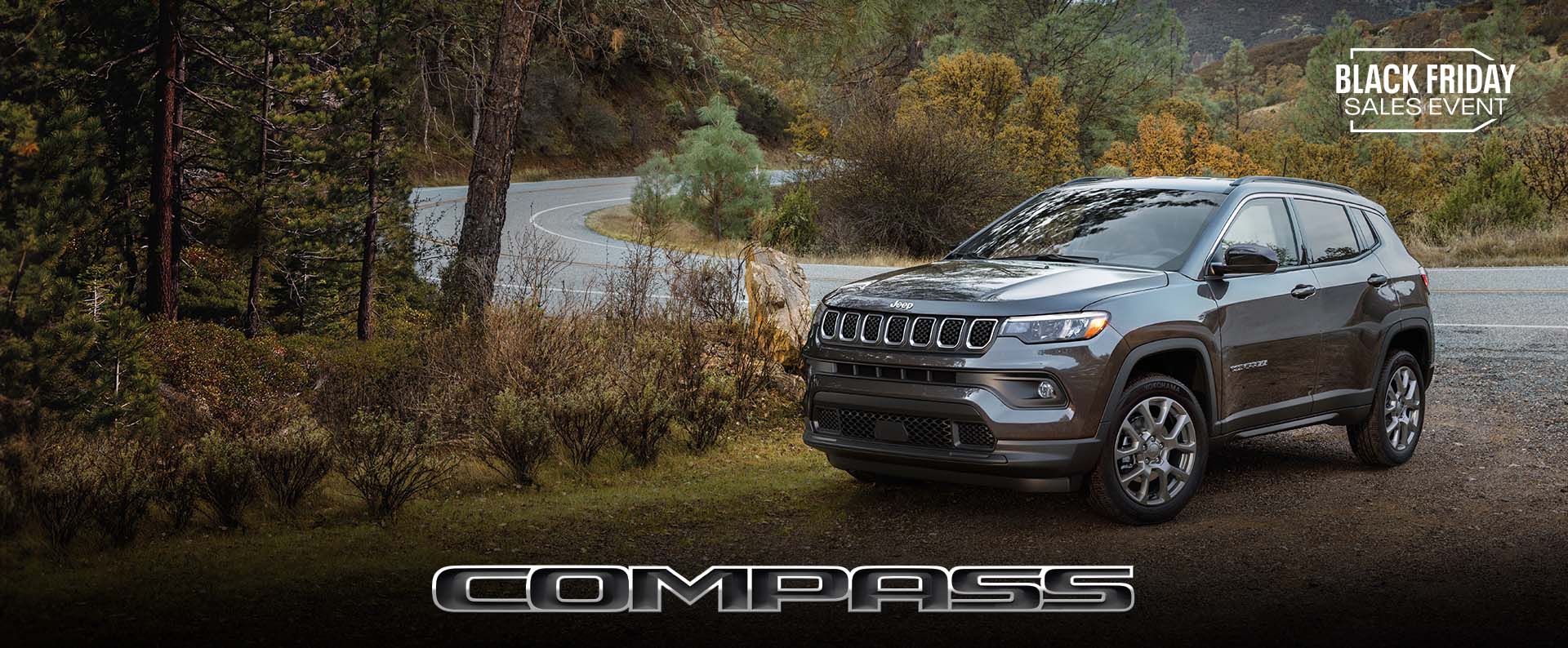 A gray 2024 Jeep Compass Latitude parked on a clearing off a winding highway. Black Friday Sales Event. Compass.
