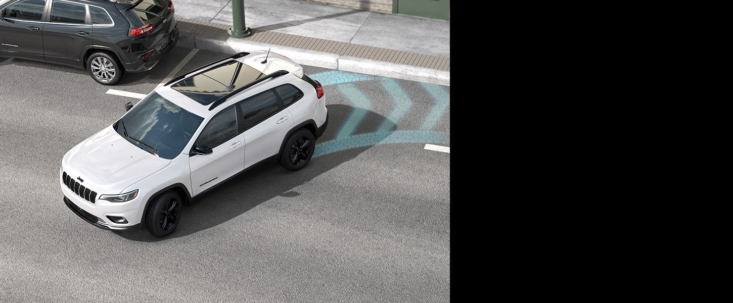 A white 2023 Jeep Cherokee Altitude Lux backing into a parallel parking spot with blue illustrated arrows representing the area monitored by sensors.