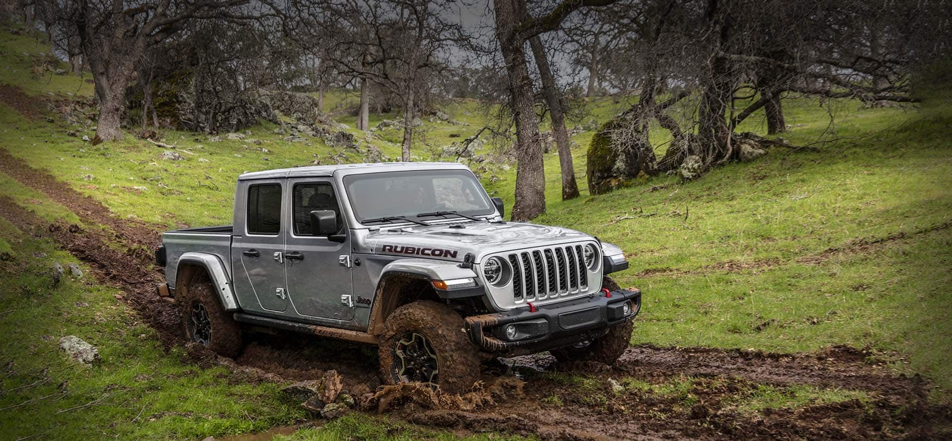 The 2023 Jeep Gladiator Rubicon being driven off-road on a muddy downhill slope.