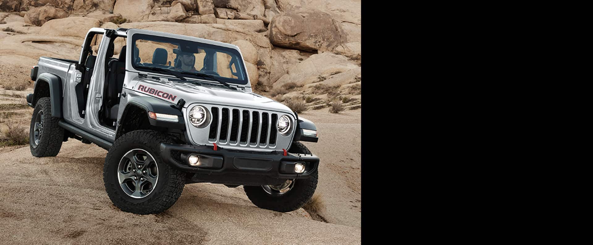 The 2023 Jeep Gladiator Rubicon parked off-road on rock with its top and doors removed.