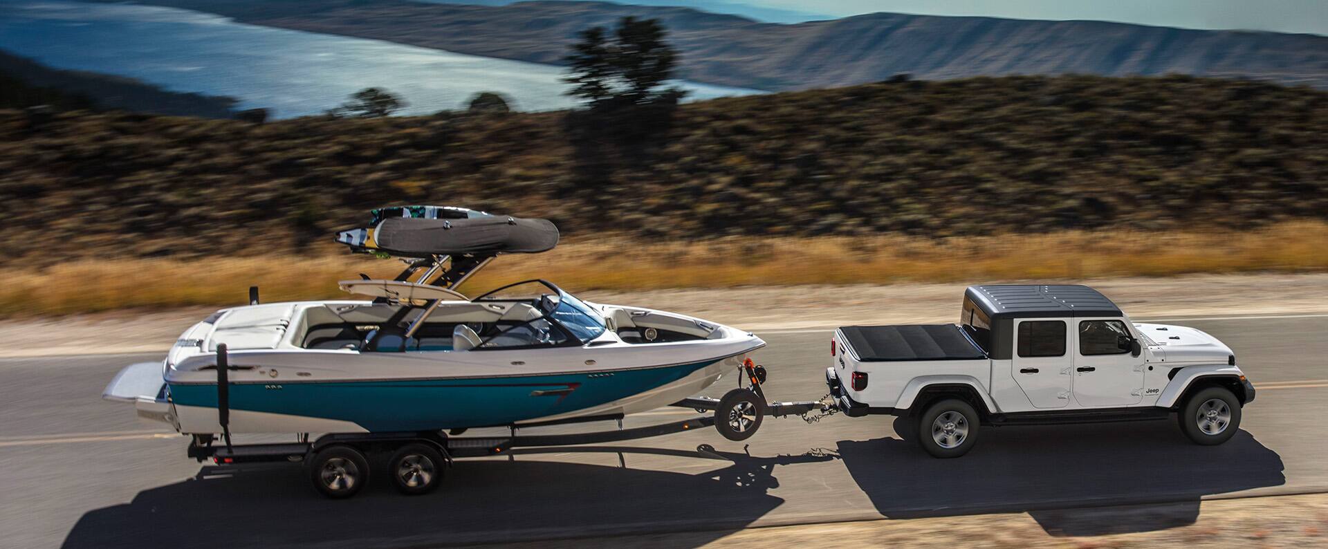 The 2023 Jeep Gladiator Overland towing a motorboat on an open road.