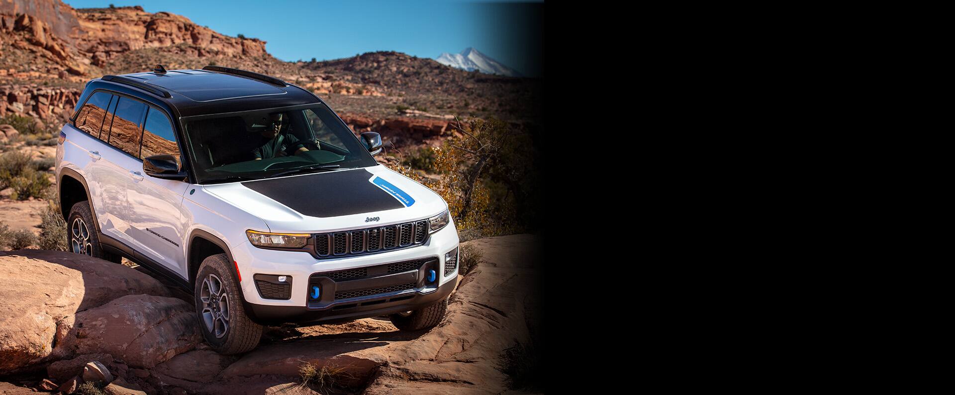 El Jeep Grand Cherokee Trailhawk 4xe 2023 escalando una piedra mientras circula sobre un sendero rocoso.