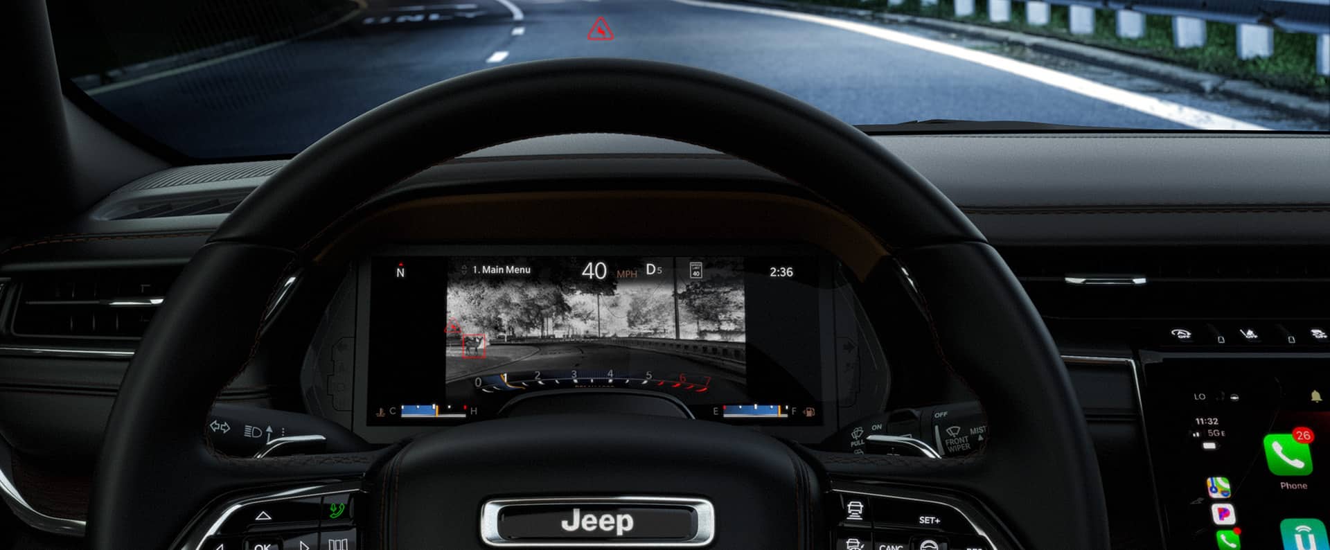 La pantalla digital con información para el conductor en el panel de instrumentos del Jeep Grand Cherokee 2023 mostrando la vista de la ruta oscurecida adelante, con obstáculos potenciales resaltados en rojo.