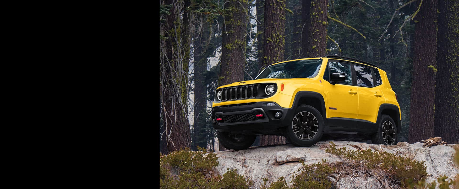 Un Jeep Renegade Trailhawk 2023 estacionado sobre una saliente rocosa en el bosque.