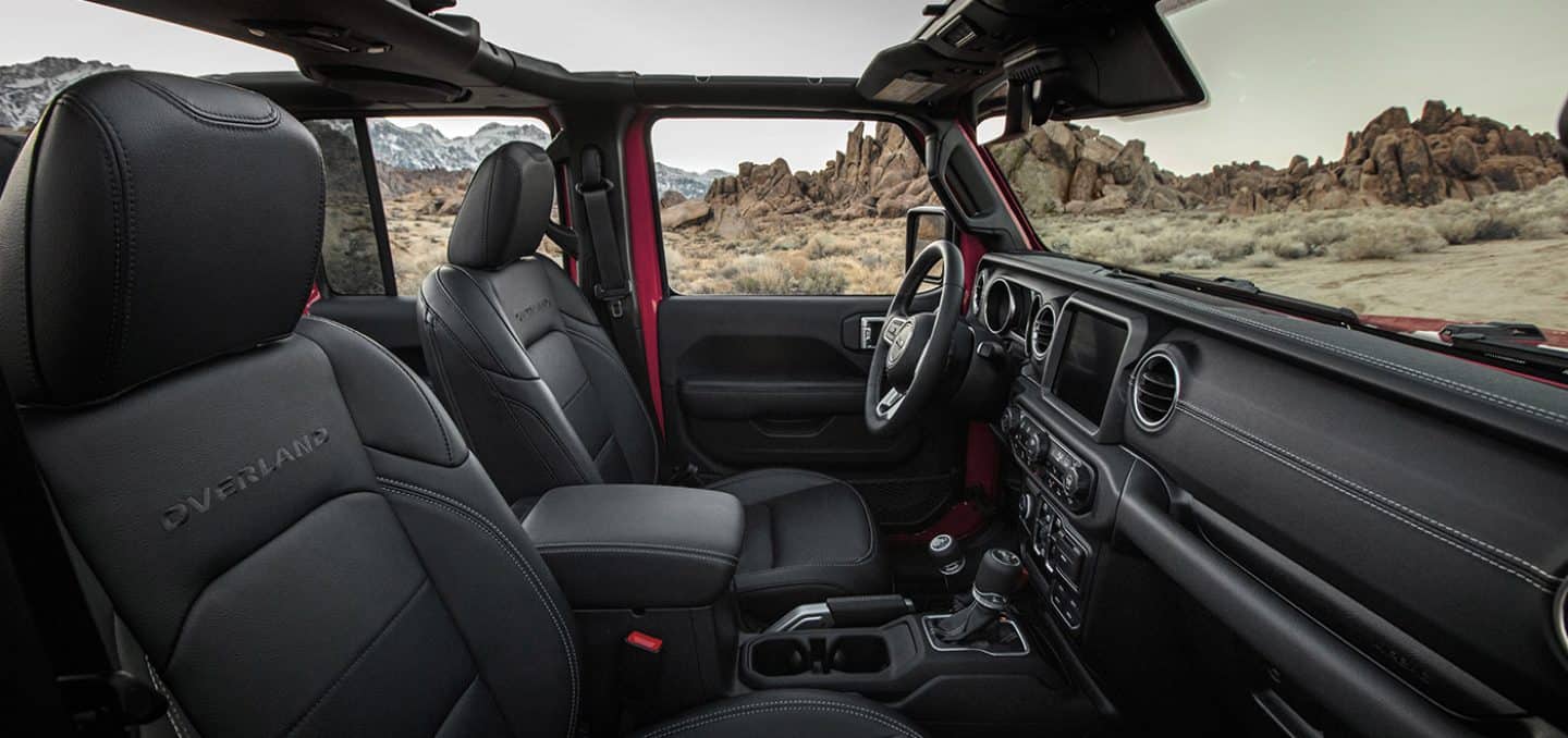 Display The interior of the 2023 Jeep Gladiator Overland with its top off, focusing on the front seats and dash.