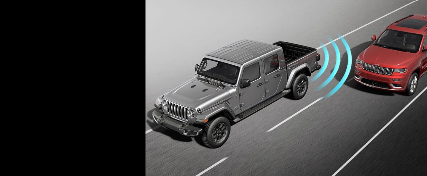 Illustrated sensor bars coming from the rear left of the 2023 Jeep Gladiator Overland, detecting an approaching vehicle in the next lane over.
